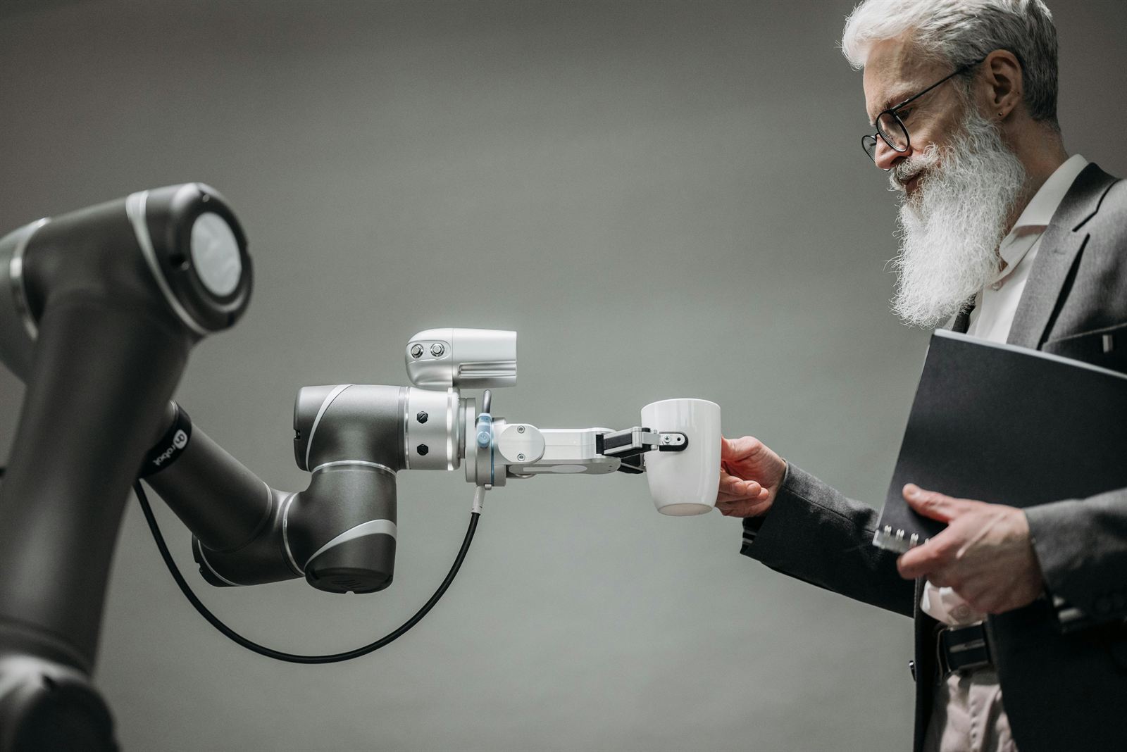 A robotic arm handing a cup to a man