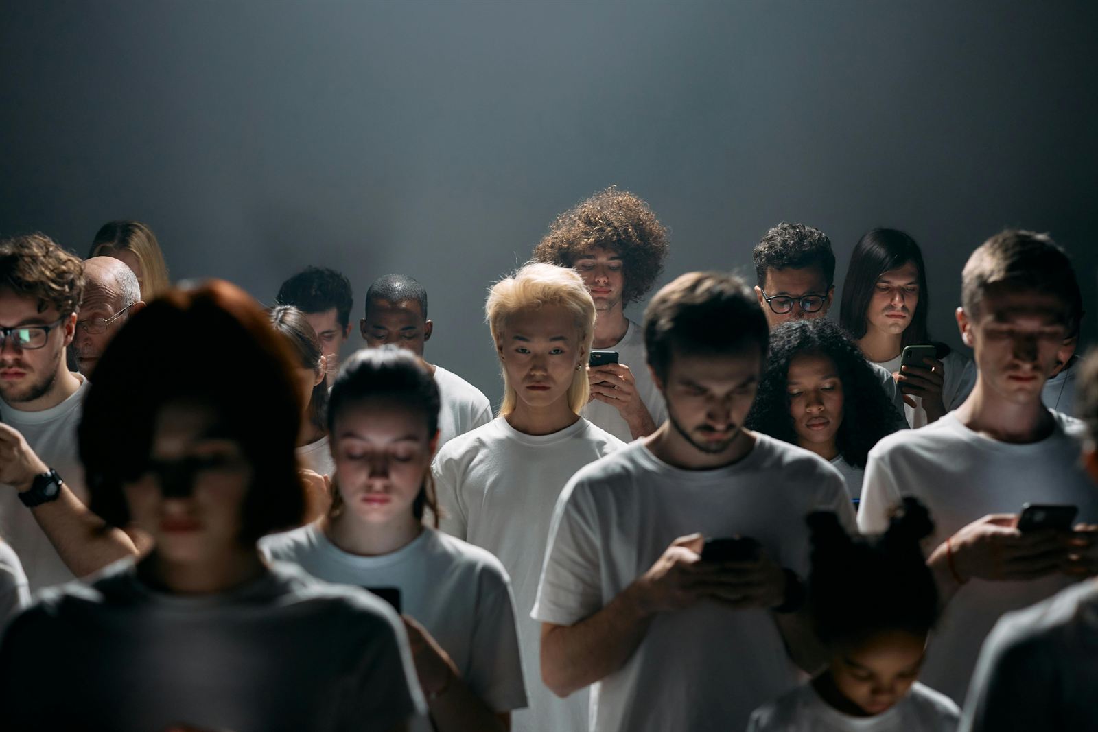 A crowd of people looking down at their phones